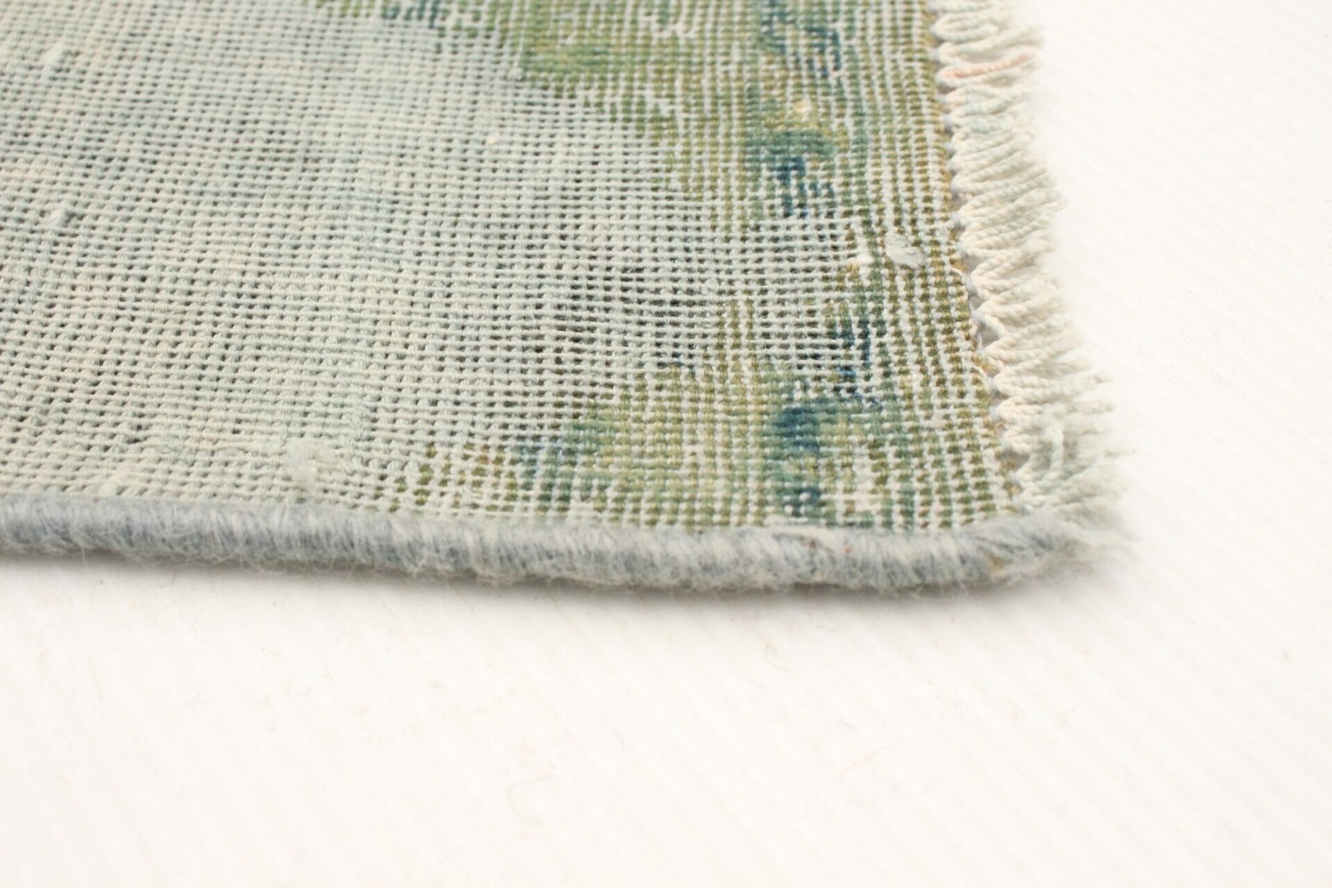 Een close up van een vloerkleed met een groen en blauw patroon.