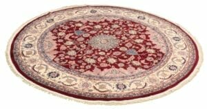 Een rond vloerkleed met een rood en beige design.