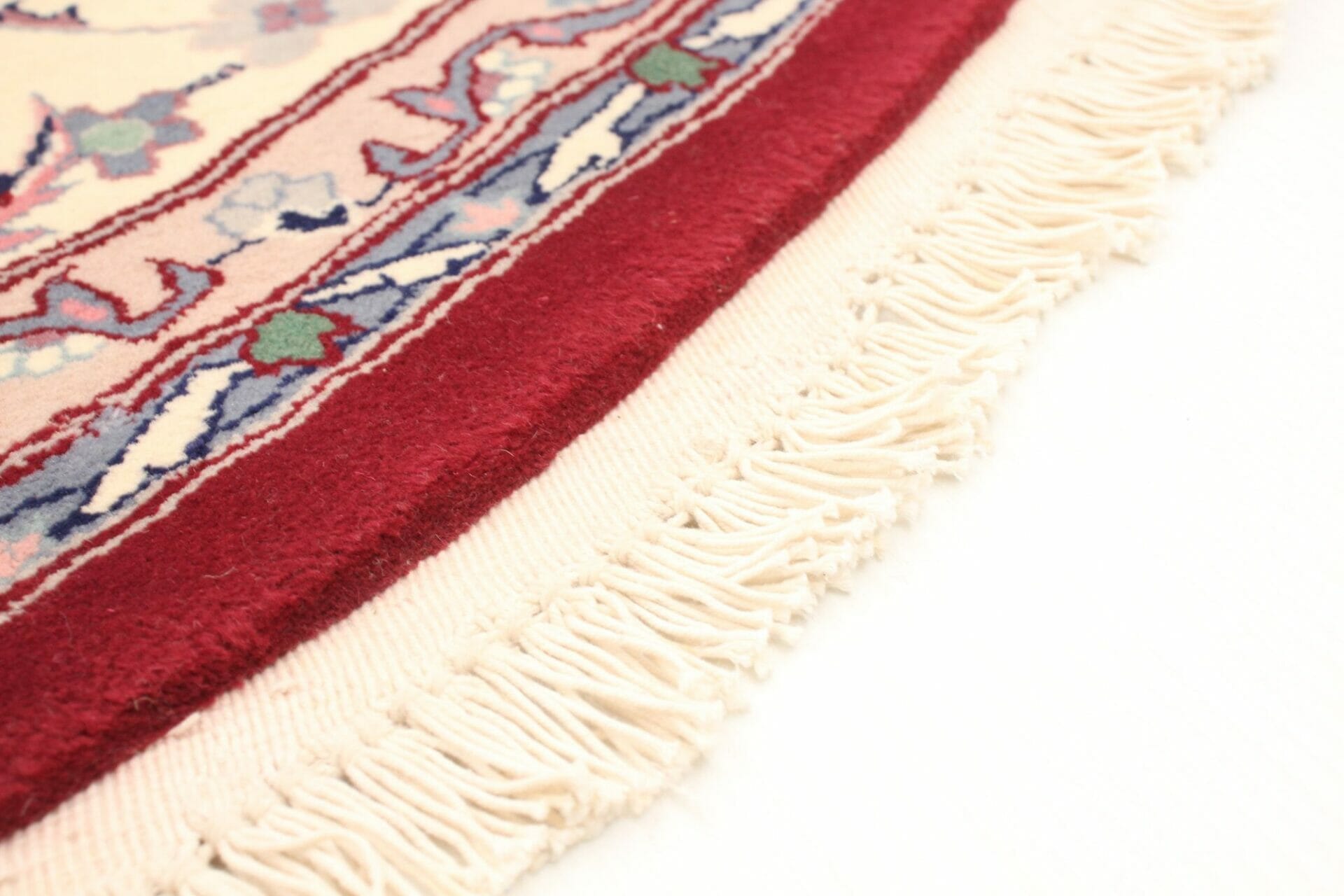 Een close up van een rood en wit vloerkleed met franjes.