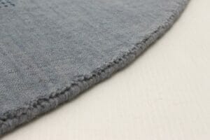         Beschrijving: Een close-up van een blauw vloerkleed op een witte ondergrond.