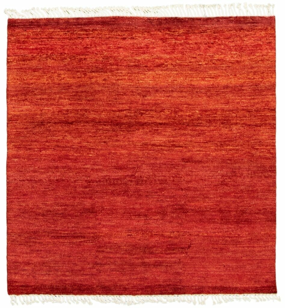 Een rood vloerkleed met franjes op een witte achtergrond.