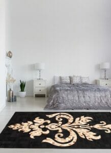 Een slaapkamer met een zwart en goud vloerkleed.