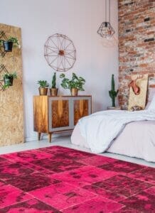 Een roze tapijt in een slaapkamer met een houten muur.