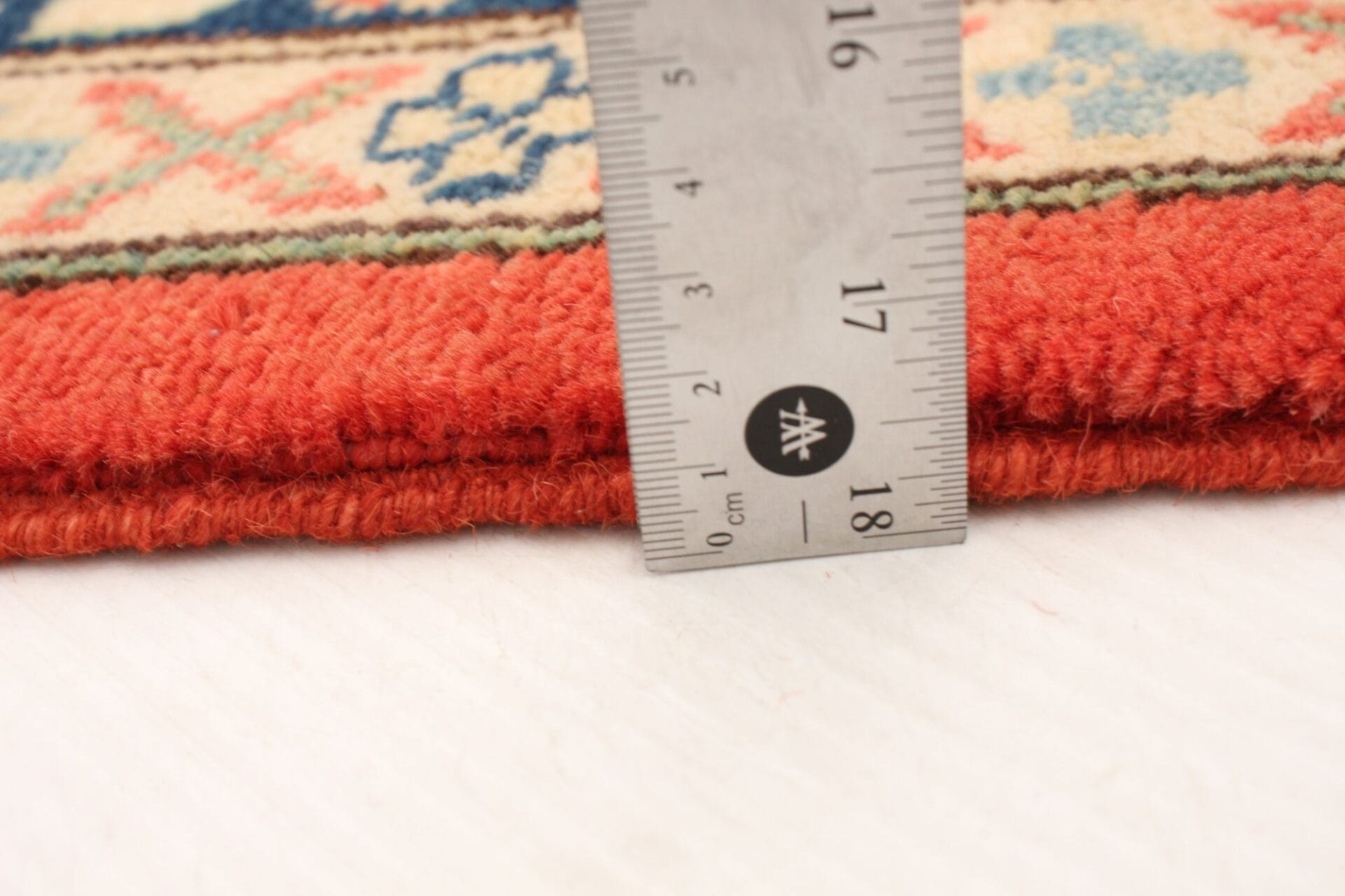 Beschrijving: Een oranje en blauw tapijt met een liniaal ernaast.