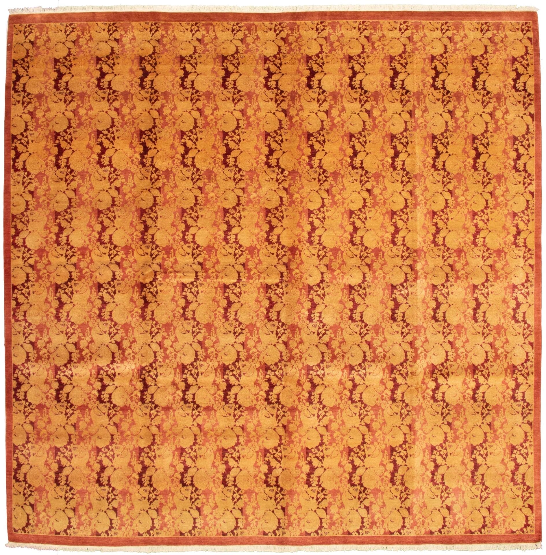 Beschrijving: Een oranje en bruin tapijt met een bloemenpatroon.