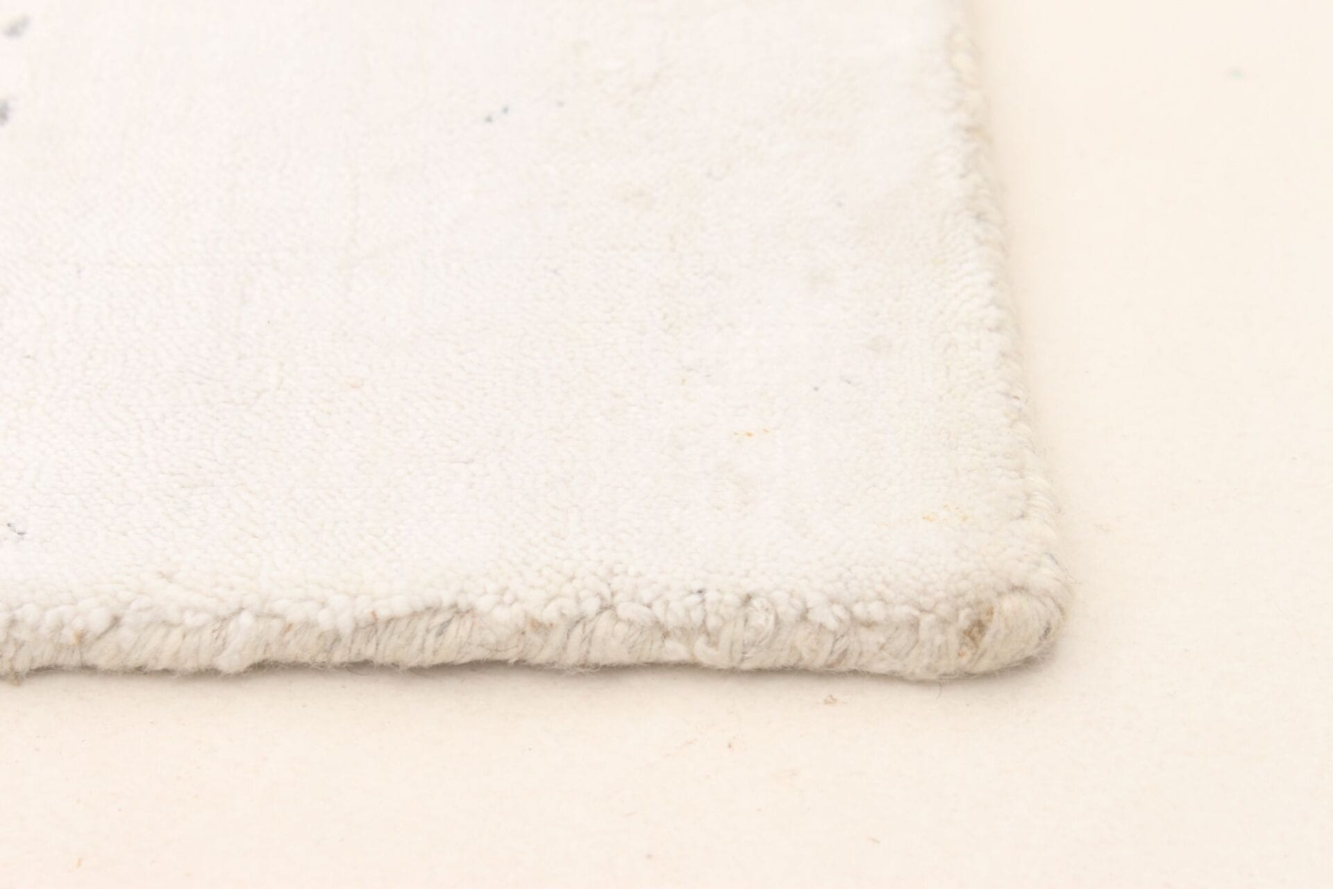 Een close up van een wit vloerkleed op een witte ondergrond.