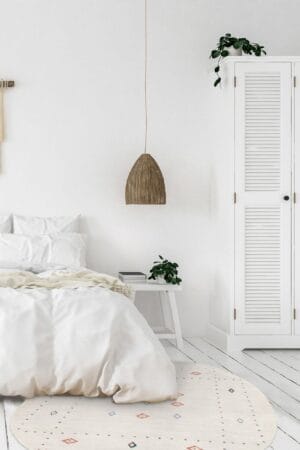 Een witte slaapkamer met een rond vloerkleed.