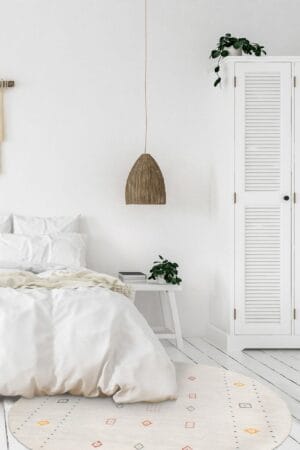 Een witte slaapkamer met een bed en een vloerkleed.