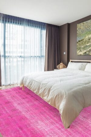 Een slaapkamer met een roze tapijt op de vloer.