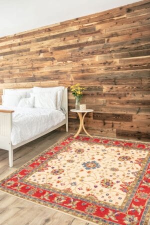 Een slaapkamer met een rood en beige tapijt voor een houten muur.