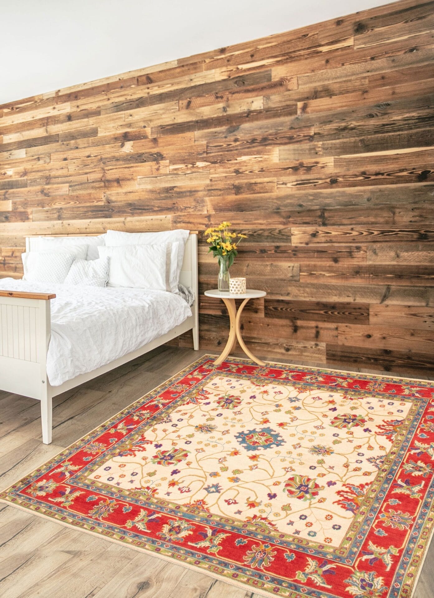 Een slaapkamer met een rood en beige tapijt voor een houten muur.