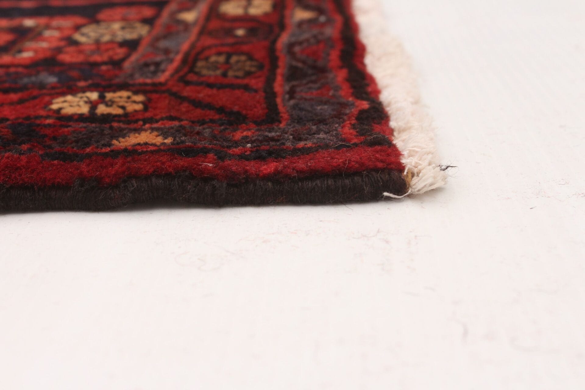 Een rood en zwart tapijt op een wit vloerkleed.