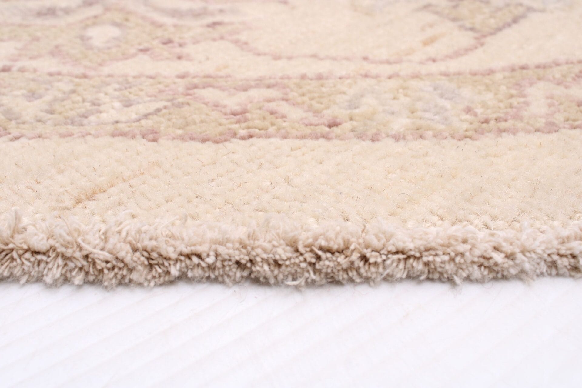 Een close up van een beige tapijt op een wit vloerkleed.