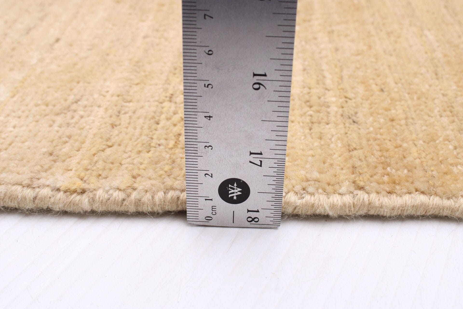 Om de lengte van een tapijt te meten, wordt een liniaal gebruikt.