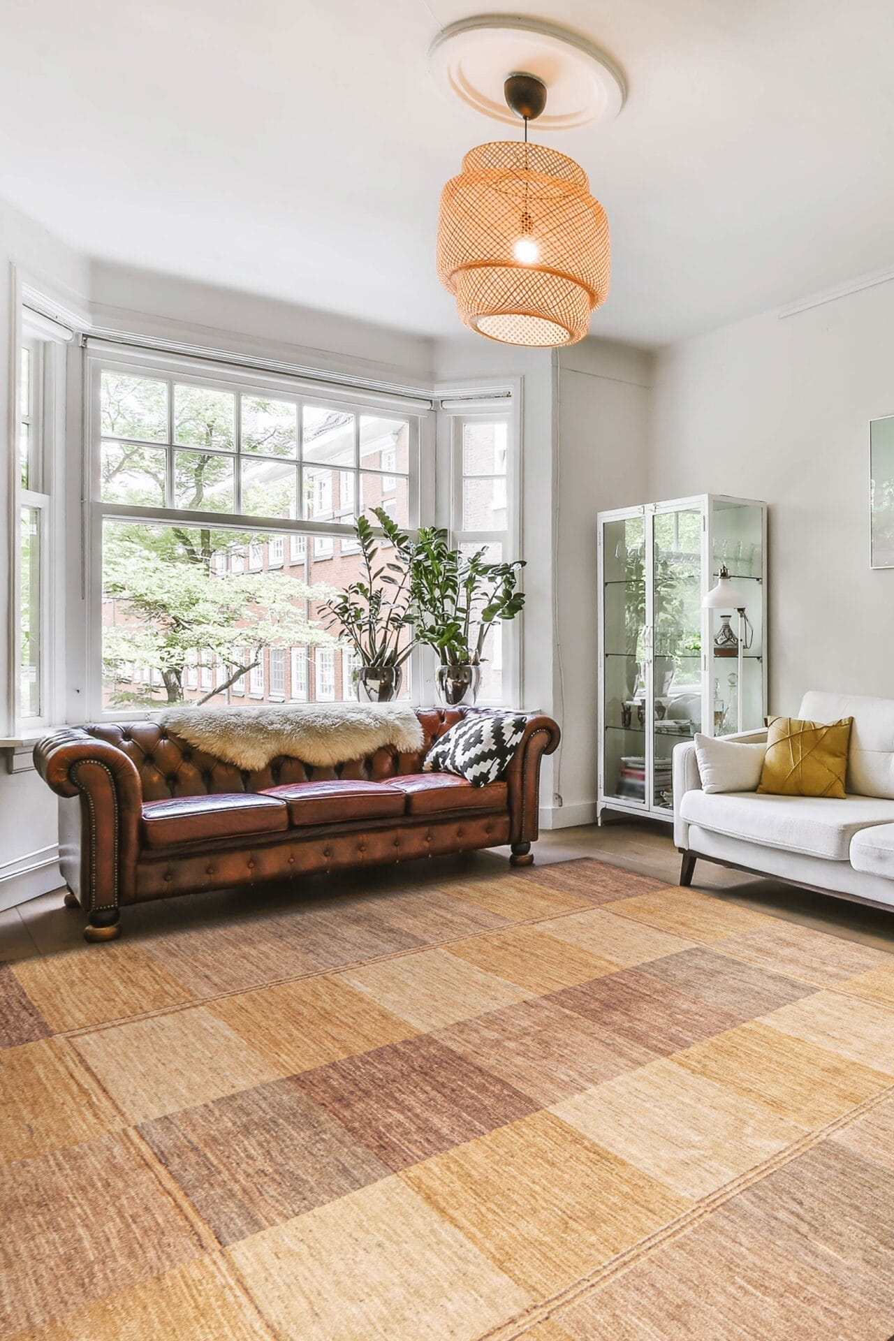 Een woonkamer met een beige en lichtbruin vloerkleed.