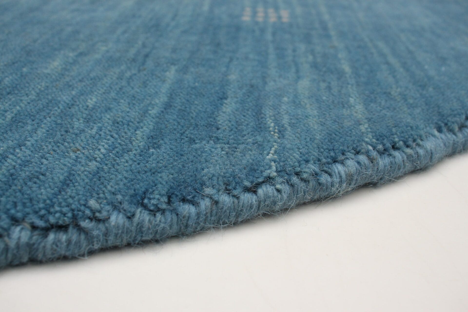Beschrijving: Een close-up van een blauw vloerkleed op een witte ondergrond.