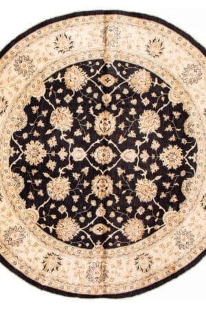 Een zwart en beige rond tapijt met bloemmotieven.