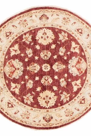 Beschrijving: Een rond tapijt met een rood en beige bloemmotief.