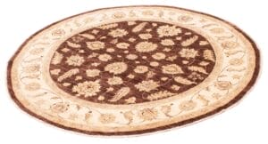 Een rond vloerkleed met bloemmotieven in bruine en beige tinten.