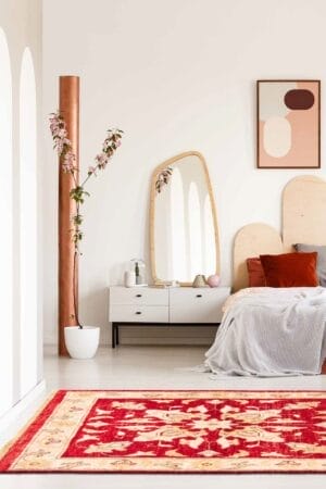 Een slaapkamer met een rood tapijt en een wit bed.