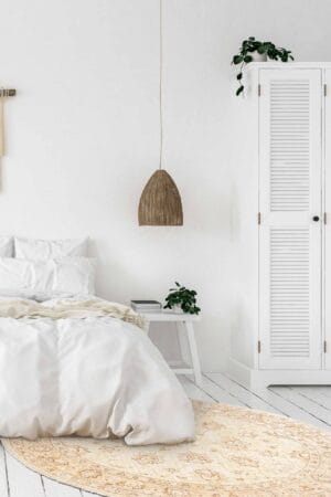 Een witte slaapkamer met een bed en een vloerkleed.