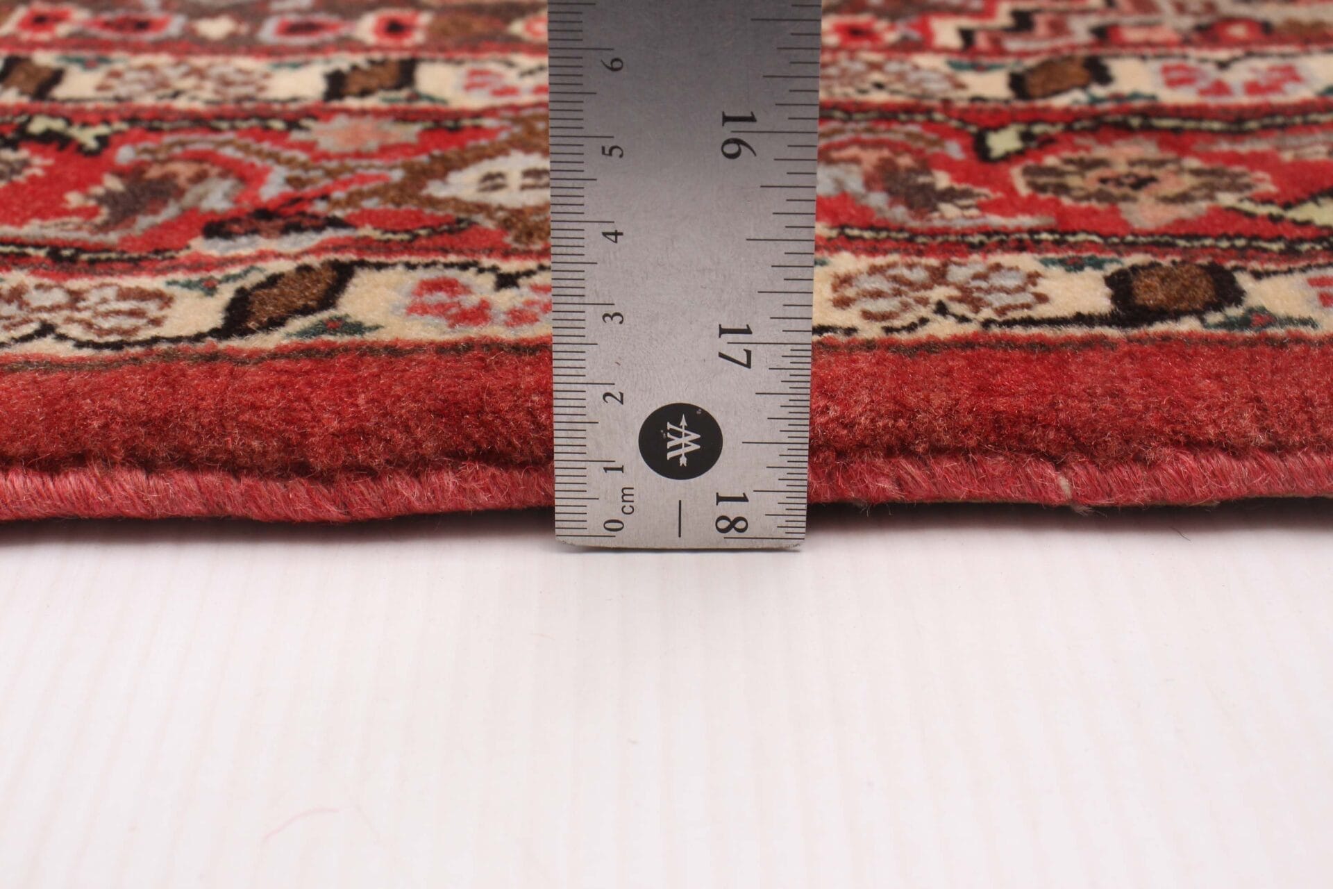 Op een rood vloerkleed wordt een liniaal geplaatst.