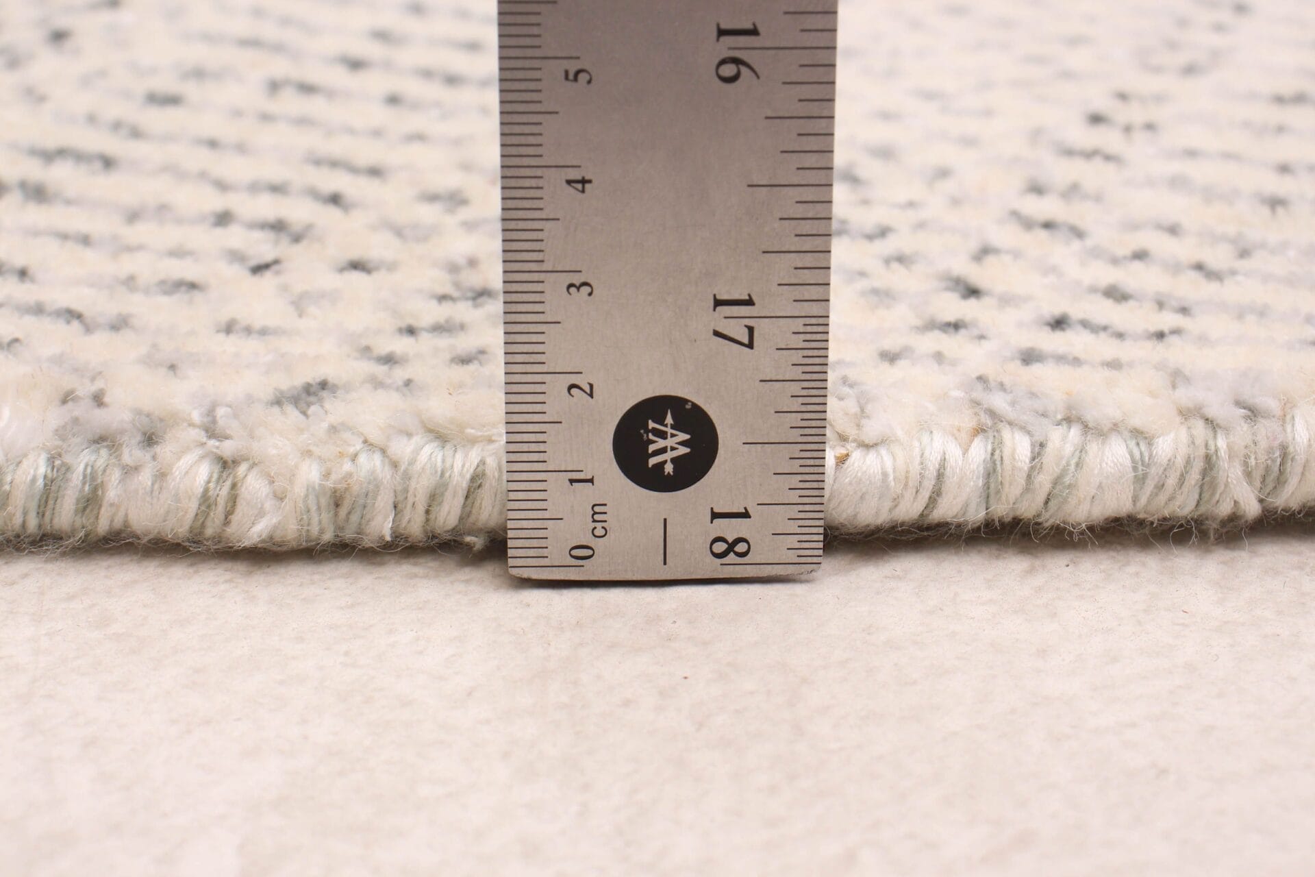 Een vloerkleed wordt gemeten met een liniaal.