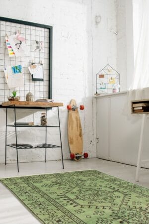 Een kamer met een groen vloerkleed en een skateboard.