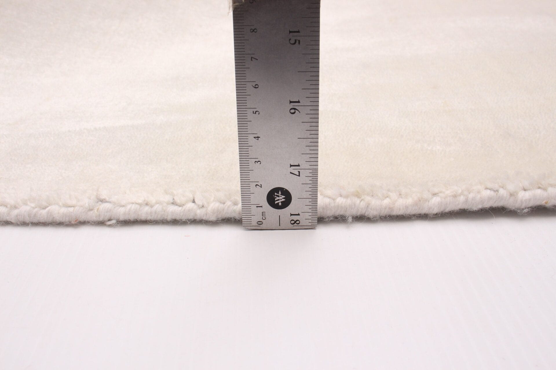 Op een wit tapijt wordt een liniaal geplaatst.