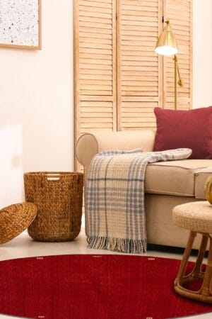 Een woonkamer met een rood tapijt en rieten mand.