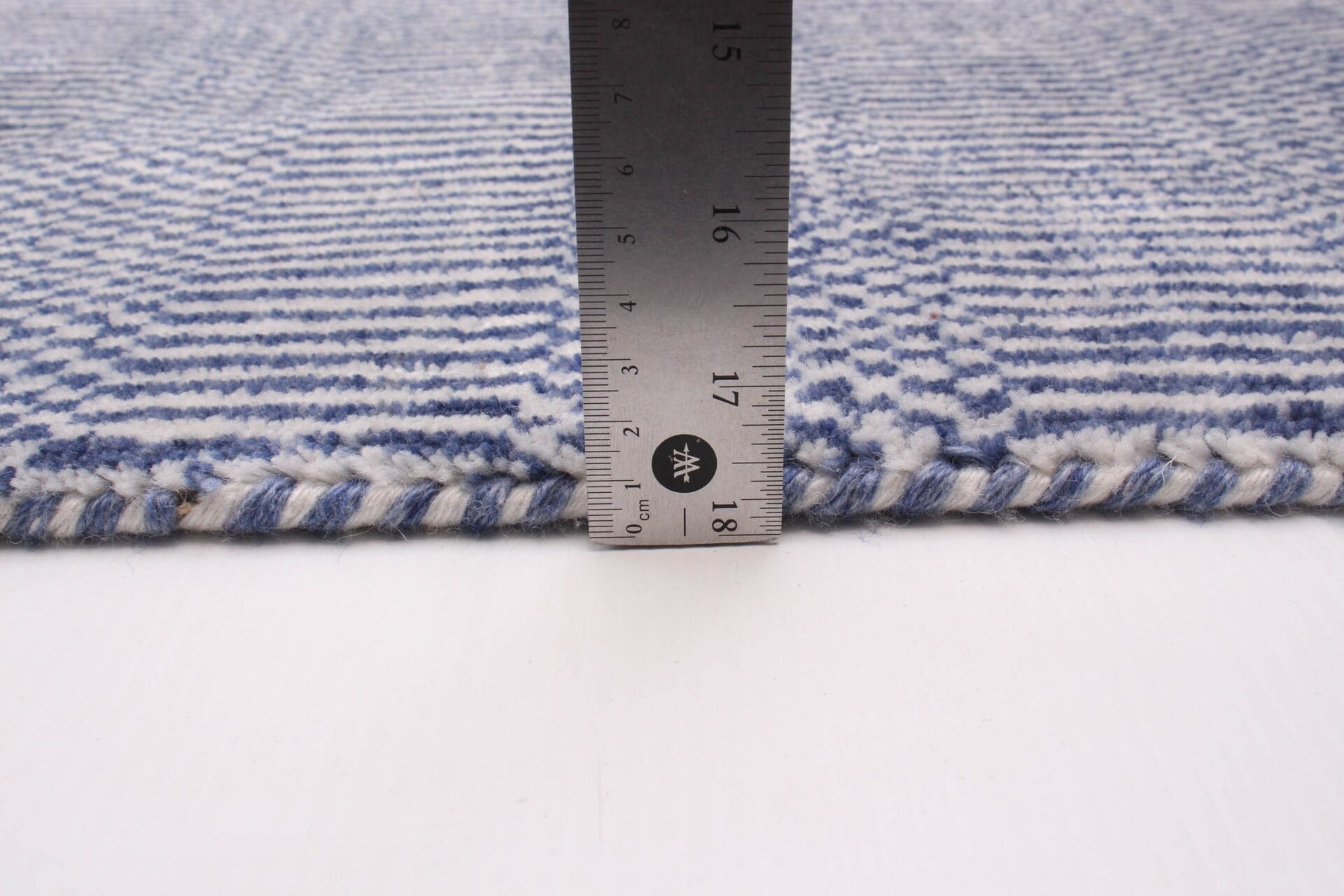 Beschrijving: Een blauw en wit vloerkleed met een liniaal erop.