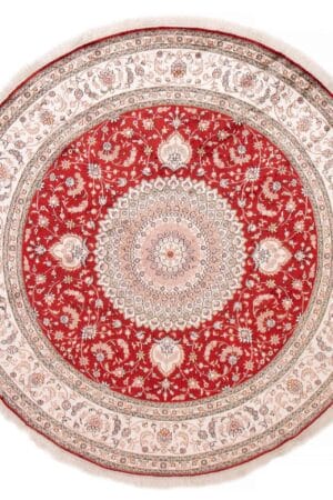 Beschrijving: Een rond tapijt met een rood en beige ontwerp.