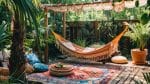 Onder een houten pergola hangt een kleurrijke hangmat, omgeven door weelderig groen, decoratieve kussens en een vloerkleed met patronen, waardoor een bohemien tuingevoel ontstaat.