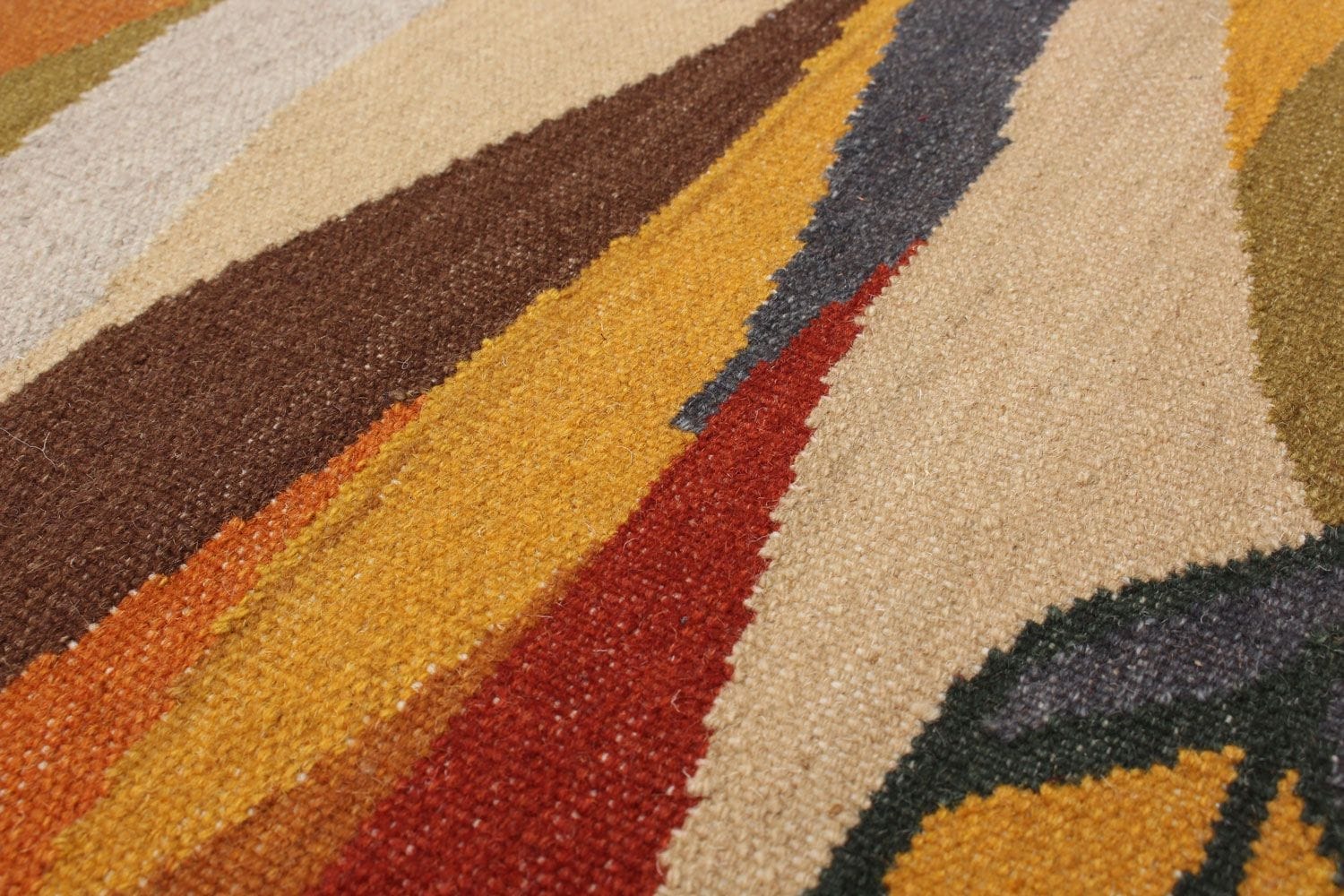 Een close-up van een veelkleurig tapijt met abstracte geometrische patronen in beige, bruine, oranje, rode, gele en groene tinten.