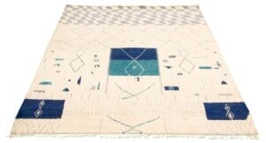 Geometrisch tapijt met franje aan de randen, met blauwe en blauwgroene vormen op een beige achtergrond.