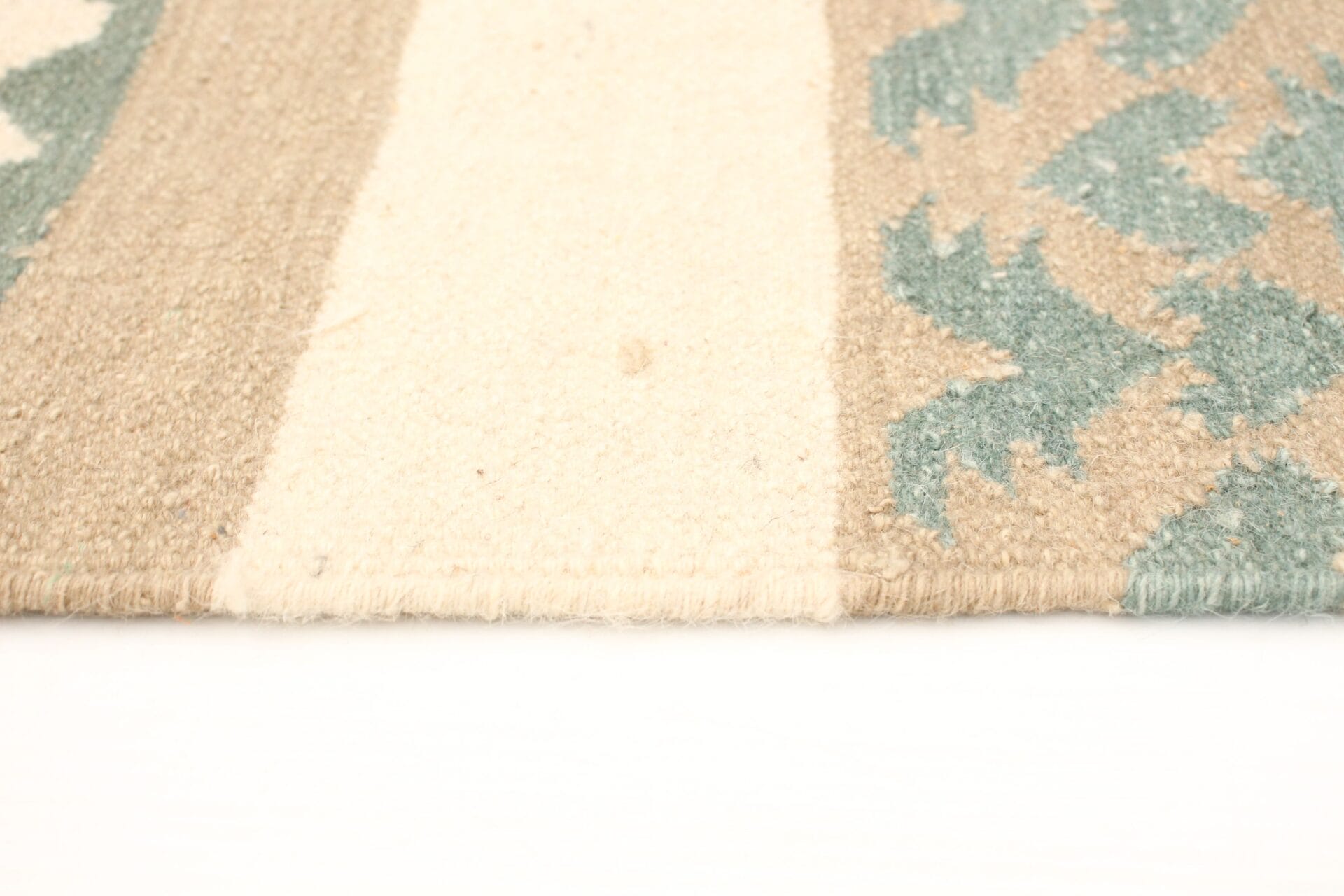 Close-up van een geweven tapijt met beige en crèmekleurige strepen en blauwe geometrische patronen.