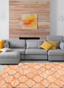 Moderne woonkamer met een grijze hoekbank, gele kussens, een abstract schilderij op een wand met houten lambrisering en een oranje vloerkleed.