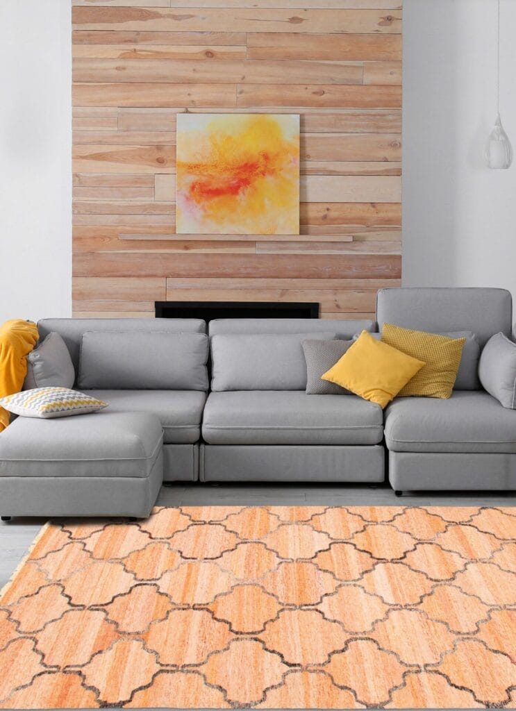 Moderne woonkamer met een grijze hoekbank, gele kussens, een abstract schilderij op een wand met houten lambrisering en een oranje vloerkleed.