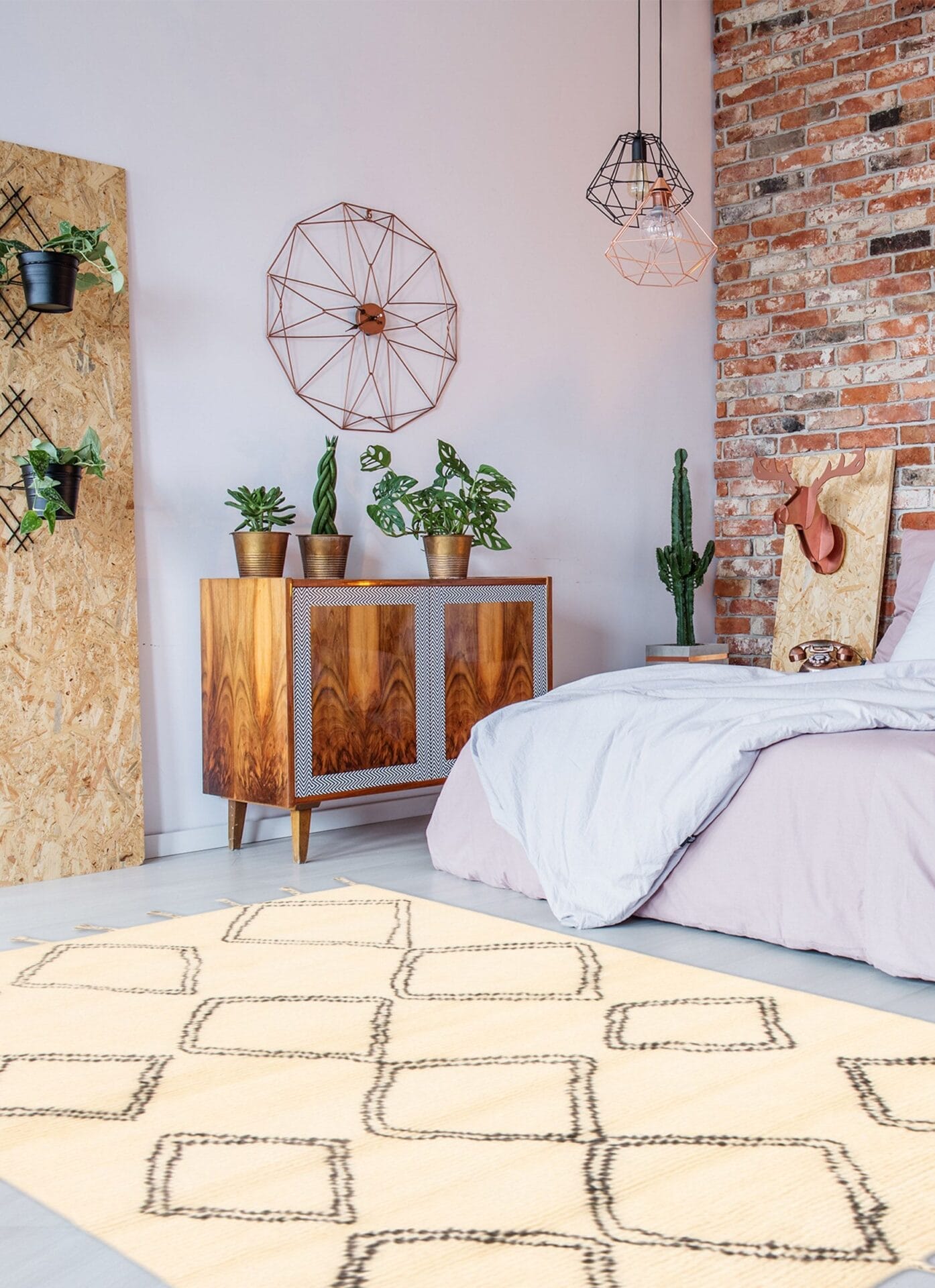 Een gezellige slaapkamer is voorzien van een bed met lichtroze beddengoed, een houten kast, cactussen en potplanten, decoratieve kunst aan de muur en accenten van baksteen en multiplex. Een licht vloerkleed met geometrische patronen bedekt de vloer en voegt warmte toe, vergelijkbaar met die van een zacht tapijt.