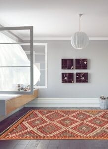 Een moderne, minimalistische kamer met een grijs kleurenschema met een vloerkleed met patronen, een zwevende houten bank, kubusvormige wandplanken en een groot raam met naar binnen waaiende vitrages.