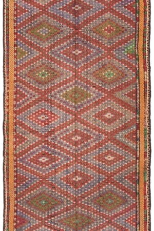 Een Turkse Konya platgeweven wollen kelim, van 183 x 348 cm, met een gedetailleerd geometrisch patroon in de kleuren rood, blauw, groen en oranje.