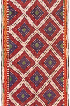 Een rechthoekige Turkse Konya platgeweven wollen wandtapijt kelim van 178 x 356 cm, met een ruitvormig patroon in rood, wit en blauw, met randen van groene, oranje en witte strepen.