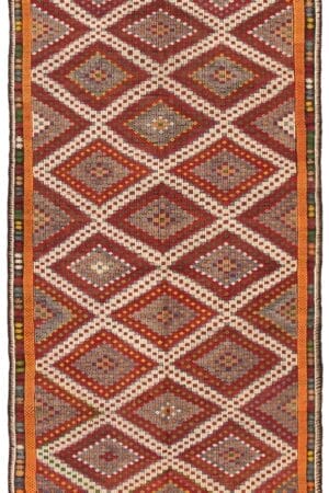 Een rechthoekige Turkse Konya platgeweven wollen kelim, 206 x 378 cm, met rode, witte, oranje, bruine en blauwe geometrische ruitpatronen met veelkleurige accenten en een oranje rand.