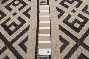 Een Pantone-stalenkaart op een zwart en beige tapijt met een patroon.