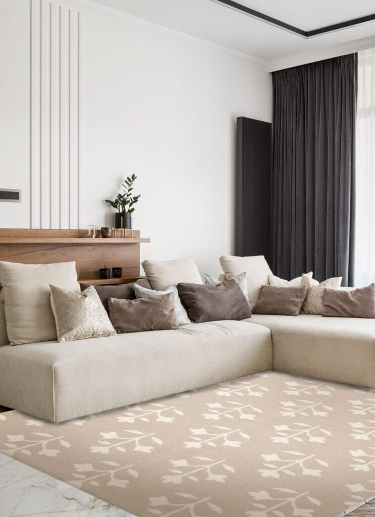 Een moderne woonkamer met een beige sectionele bank met meerdere kussens in neutrale tinten, een kleine plant op een houten plank, donkere kamerhoge gordijnen en een beige vloerkleed met een patroon.