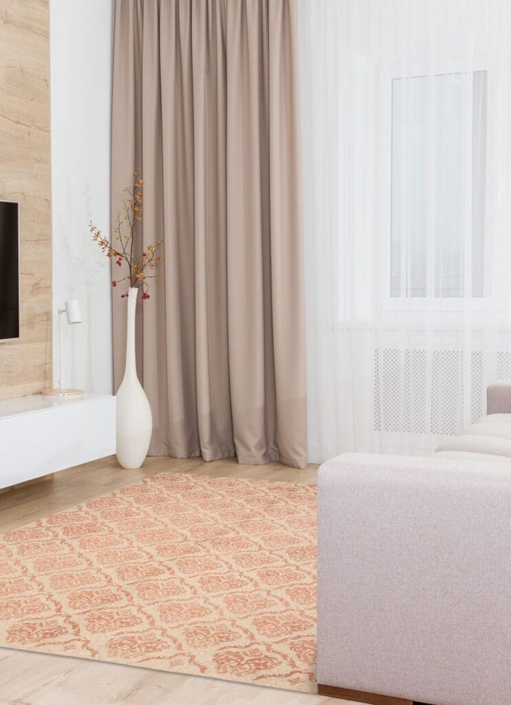 Woonkamer met beige bank, oranje vloerkleed, grote vaas met takken, gordijnen tot op de grond en een tv aan de muur.