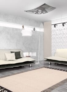 Moderne woonkamer met twee banken, een staande lamp en een decoratief tapijt op een grijze houten vloer. Een muur met geometrische patronen en een plafondarmatuur maken het minimalistische decor compleet.