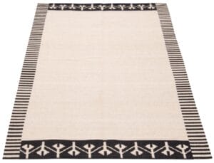 Een rechthoekig, beige tapijt met een zwarte rand met geometrische patronen en verticale strepen.