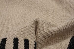 Close-up van een beige geweven stof met een zwart strepenpatroon.