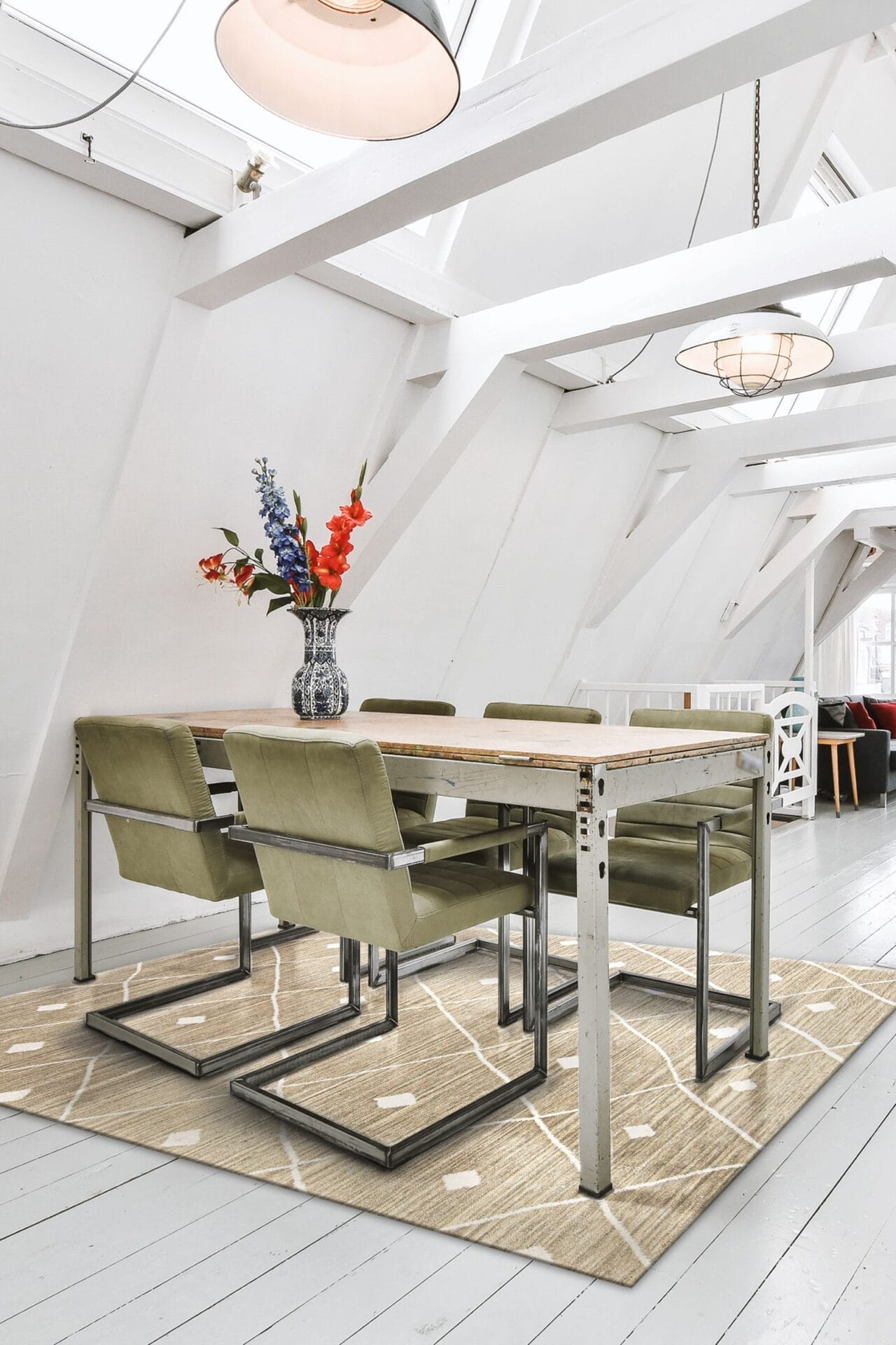 Een moderne eetkamer is voorzien van een rechthoekige houten tafel met zes groen gestoffeerde stoelen op een beige tapijt. Een vaas met rode en blauwe bloemen siert de tafel en de kamer heeft witte muren en schuine plafonds.